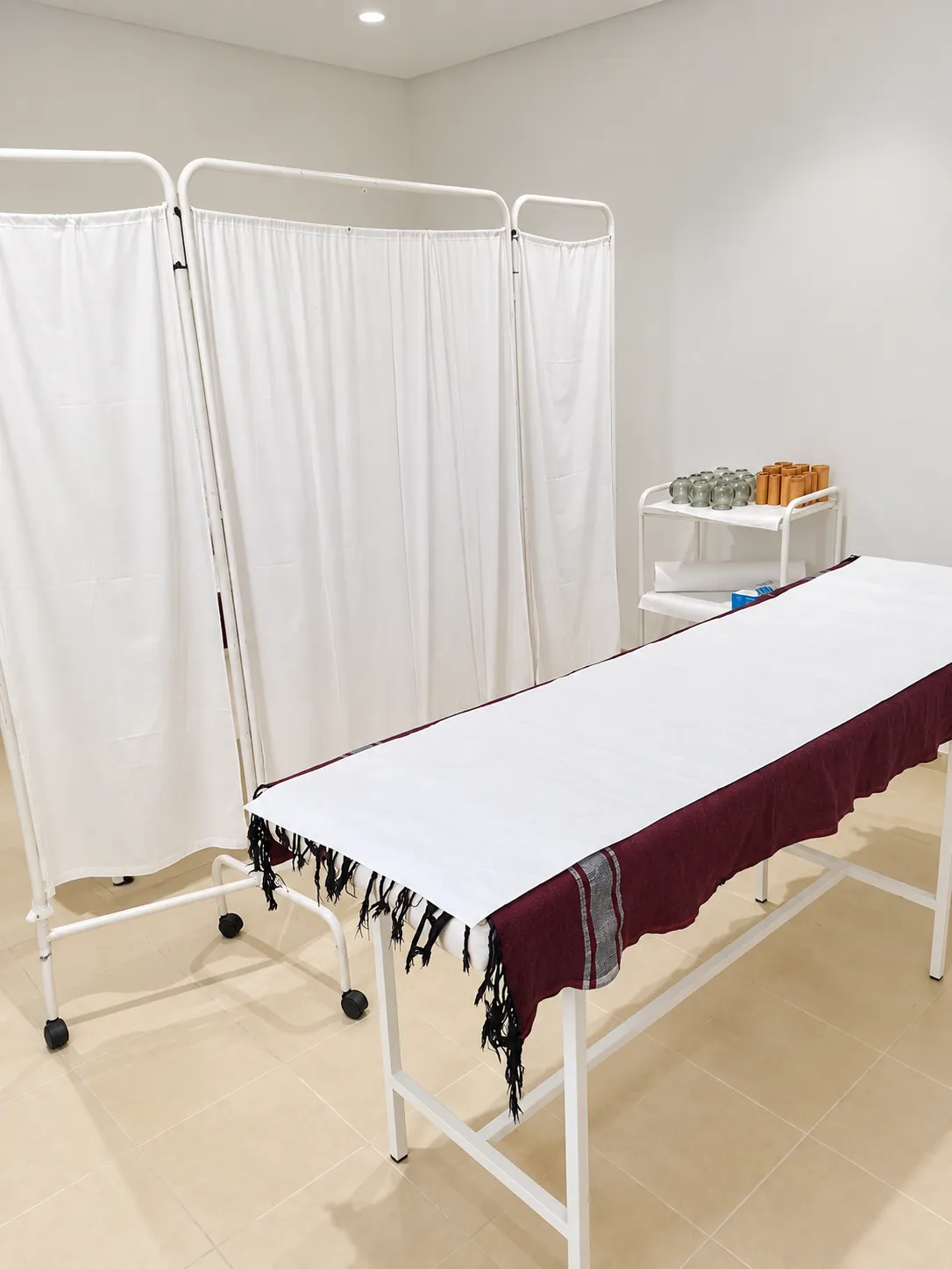 Table de soins et paravent blanc dans une salle Relaxeo