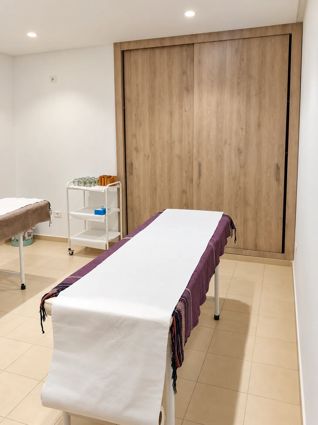 Table de massage préparée devant un placard en bois dans une salle de soins Relaxeo